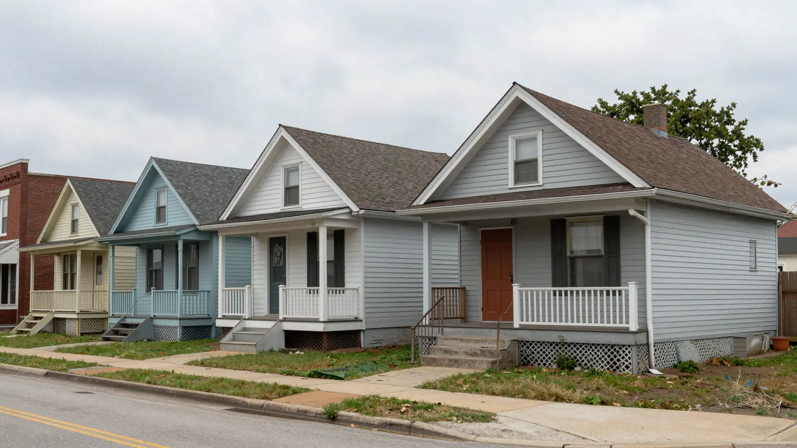 Small older frame houses with front porches close together on a narrow street with a brick corner building