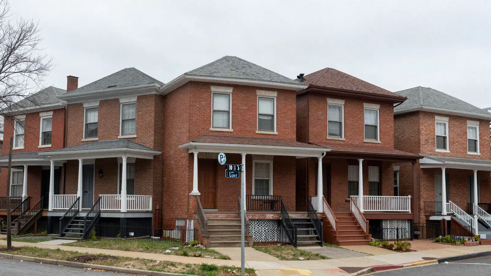 Early 1900s brick two-family houses with front stoops on a steep hillside street