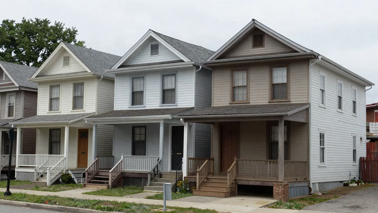 Narrow early 1900s two-family houses with stacked front porches close together on a dense street